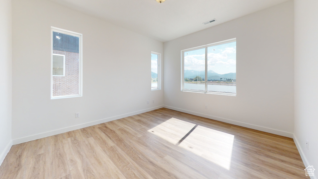 Spare room featuring a water view, a wealth of natural light, and light wood-type flooring