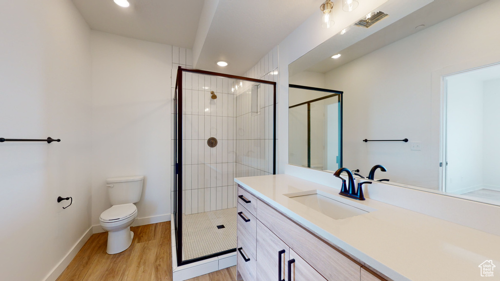 Bathroom with vanity, toilet, hardwood / wood-style floors, and an enclosed shower
