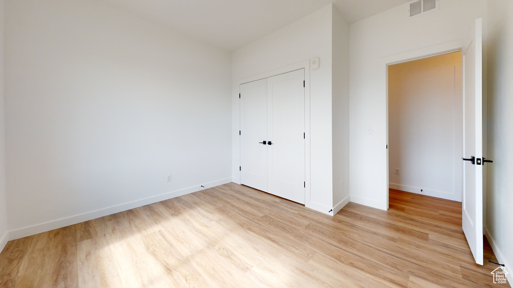 Unfurnished bedroom with light wood-type flooring and a closet