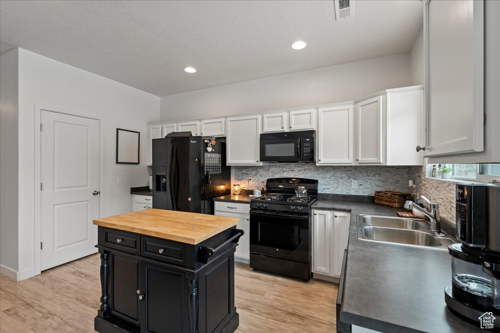 Kitchen with black appliances, light hardwood / wood-style flooring, sink, tasteful backsplash, and white cabinetry