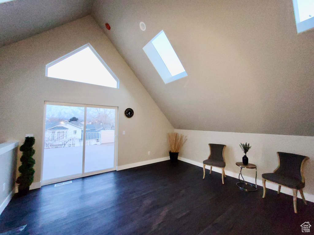 Bonus room featuring dark wood-type flooring, a skylight, and high vaulted ceiling