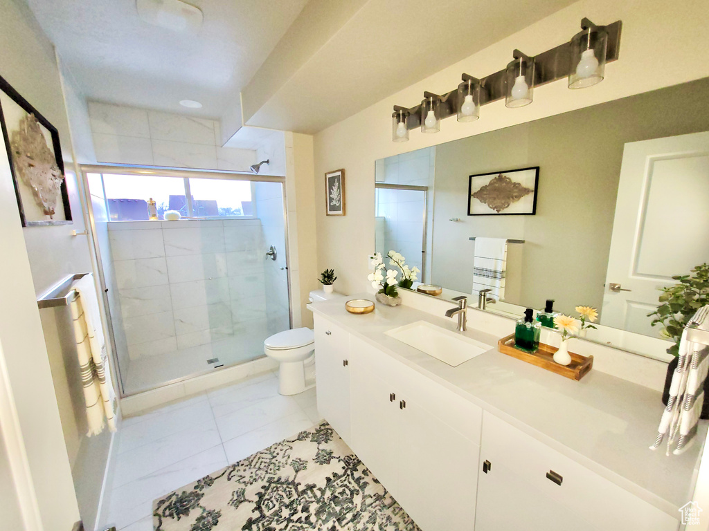 Bathroom with a shower with shower door, oversized vanity, toilet, and tile floors
