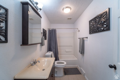 Full bathroom with toilet, vanity with extensive cabinet space, shower / bath combo, tile flooring, and a textured ceiling