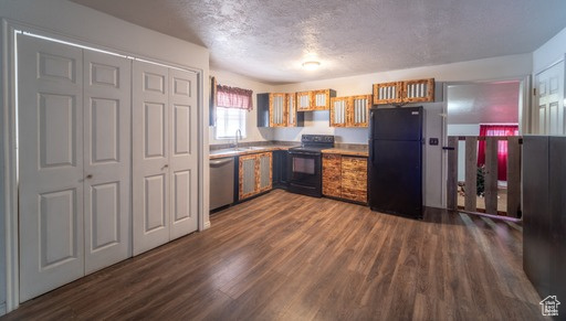 Kitchen with dark wood-type flooring, range with electric stovetop, stainless steel dishwasher, and black fridge