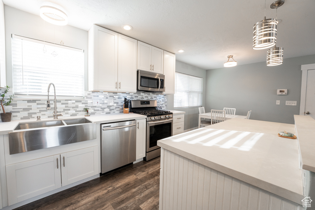 Kitchen featuring dark hardwood / wood-style flooring, stainless steel appliances, backsplash, sink, and white cabinetry
