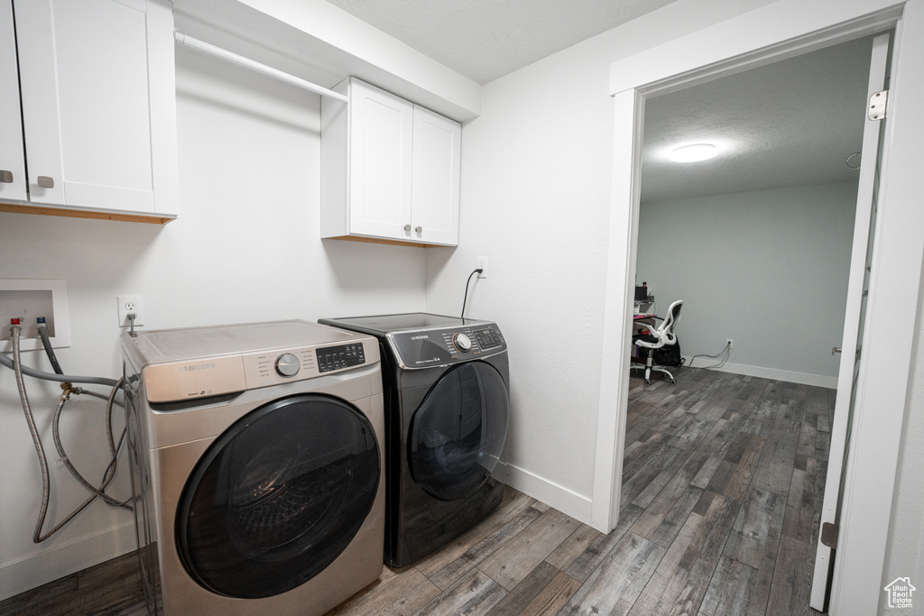 Washroom featuring dark hardwood / wood-style floors, cabinets, hookup for a washing machine, and washing machine and dryer
