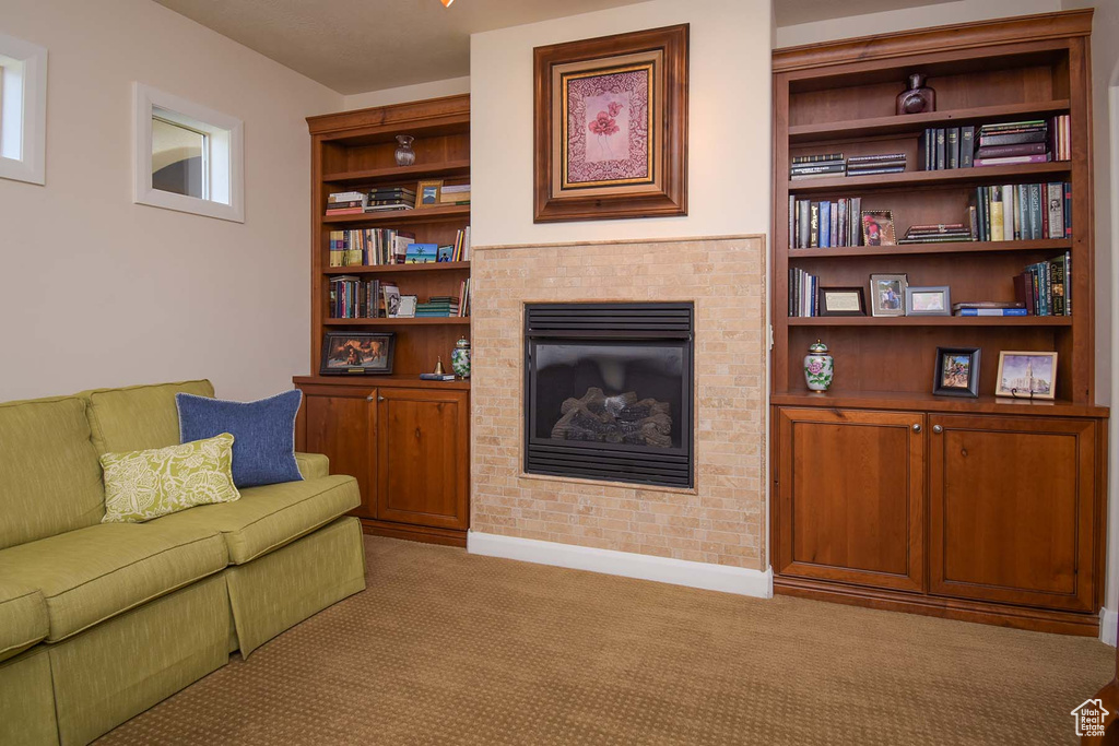 Living room featuring a brick fireplace, built in shelves, and light carpet