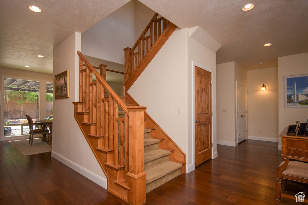 Staircase featuring dark hardwood / wood-style flooring and a textured ceiling