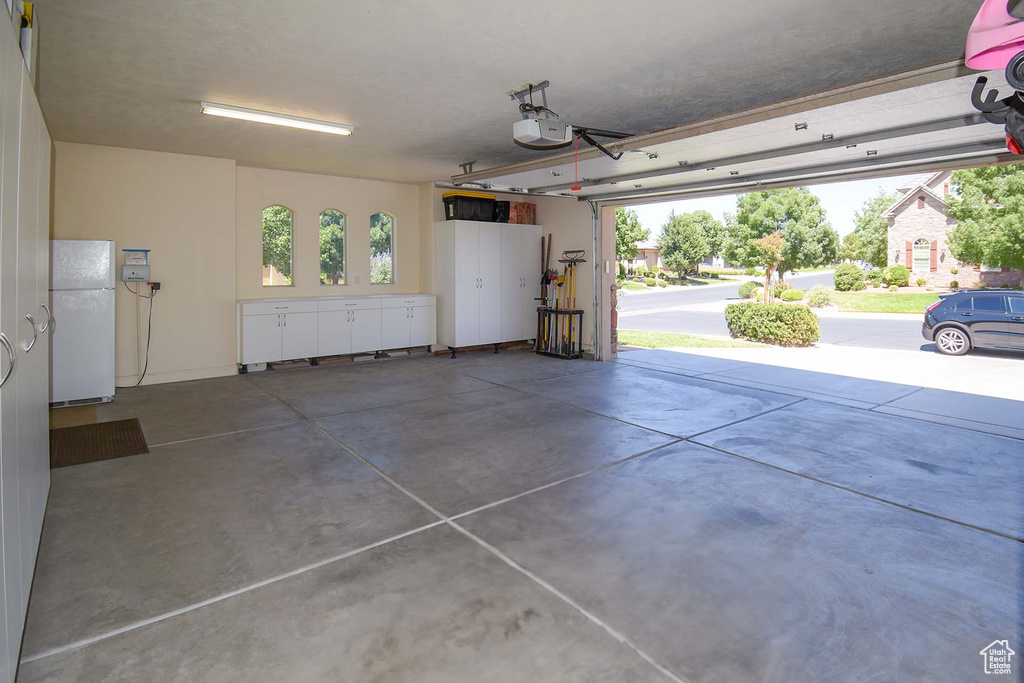 Garage with a garage door opener and white refrigerator