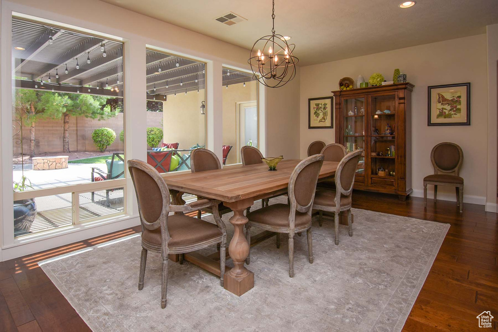 Dining space with a notable chandelier and dark hardwood / wood-style floors