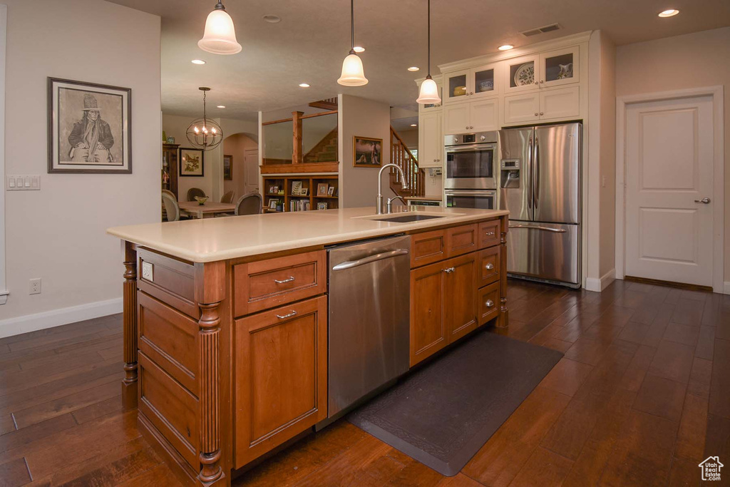 Kitchen with white cabinetry, dark wood-type flooring, a center island with sink, sink, and stainless steel appliances