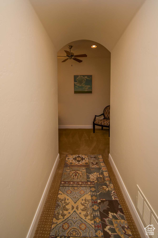 Corridor featuring dark carpet and lofted ceiling