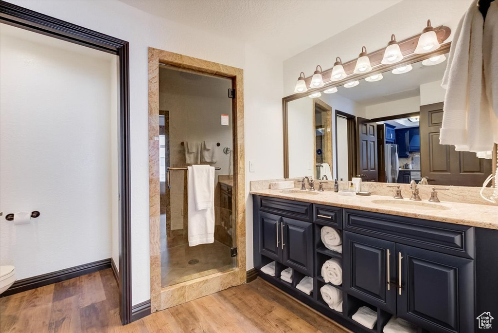 Bathroom with dual bowl vanity, walk in shower, toilet, and hardwood / wood-style floors