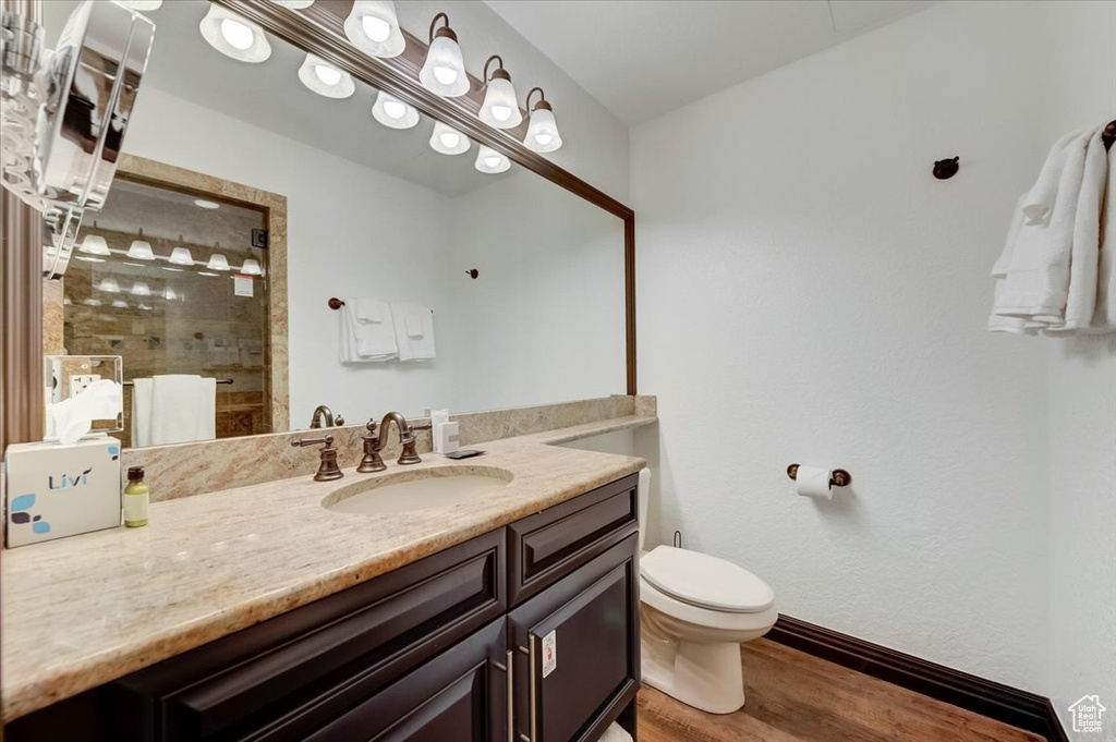 Bathroom with vanity, toilet, walk in shower, and hardwood / wood-style floors
