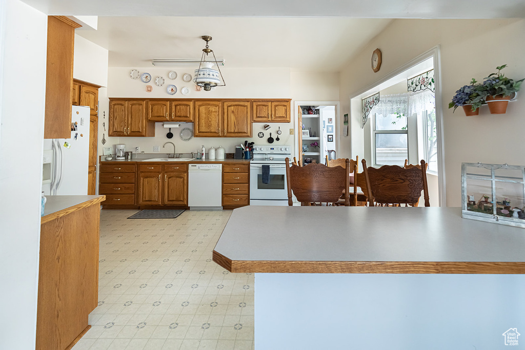 Kitchen with sink, hanging light fixtures, white appliances, and light tile floors