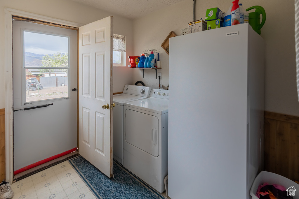 Laundry room with washing machine and clothes dryer and light tile flooring