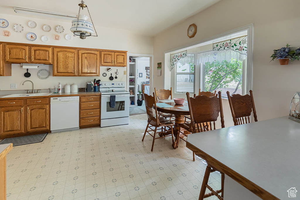 Kitchen featuring light tile flooring, sink, hanging light fixtures, and white appliances