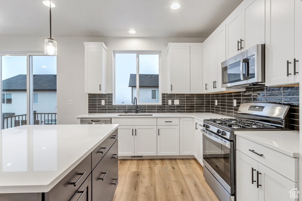 Kitchen with tasteful backsplash, light hardwood / wood-style floors, appliances with stainless steel finishes, and a healthy amount of sunlight