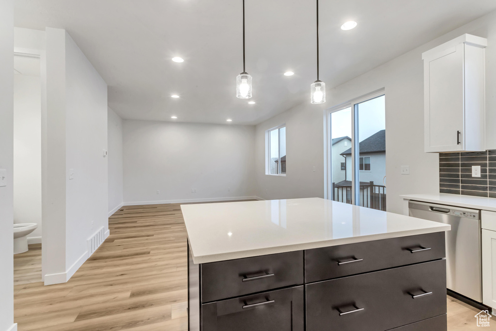Kitchen featuring dishwasher, light hardwood / wood-style floors, pendant lighting, backsplash, and white cabinetry