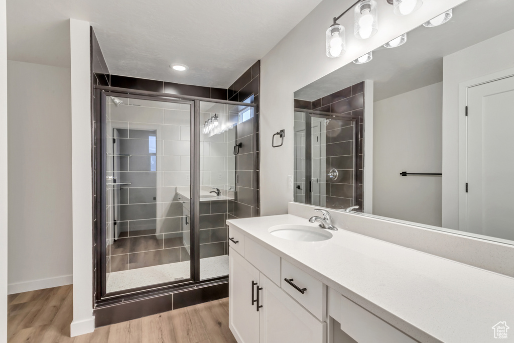 Bathroom with hardwood / wood-style floors, oversized vanity, and an enclosed shower