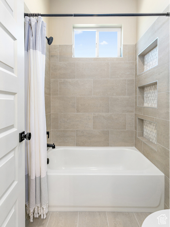Bathroom with tile flooring and shower / bath combo with shower curtain