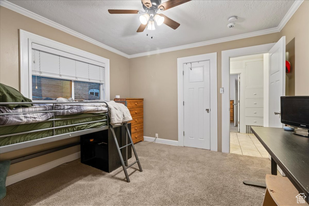 Bedroom featuring ornamental molding, light colored carpet, a textured ceiling, and ceiling fan