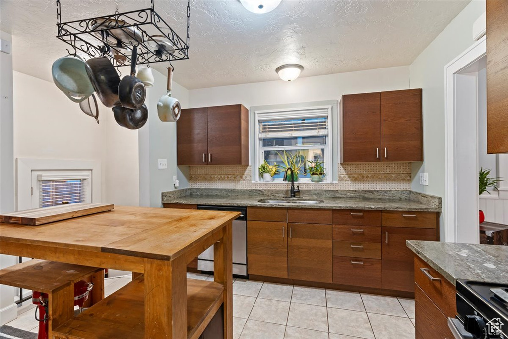 Kitchen with dishwasher, a textured ceiling, light tile floors, sink, and tasteful backsplash
