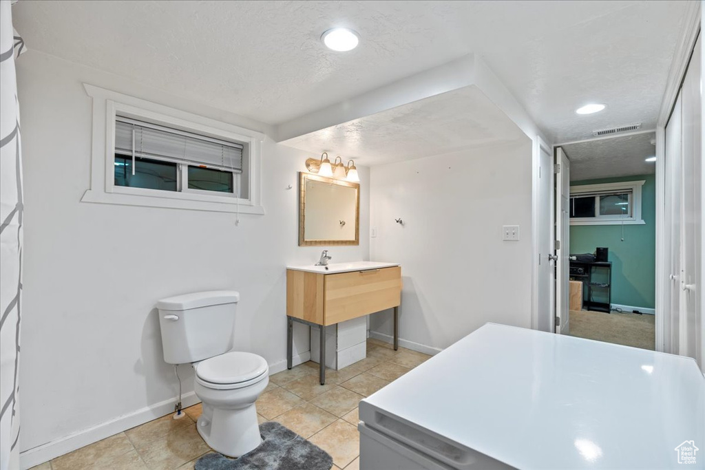 Bathroom with tile floors, toilet, large vanity, and a textured ceiling
