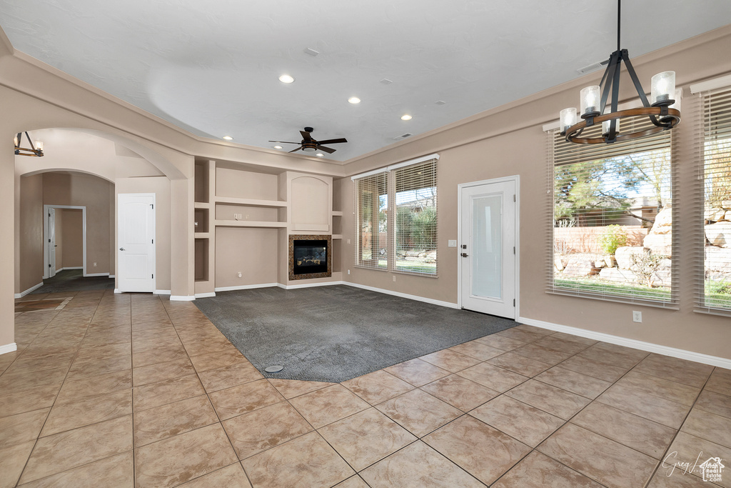 Interior space featuring built in features, light tile floors, and ceiling fan with notable chandelier