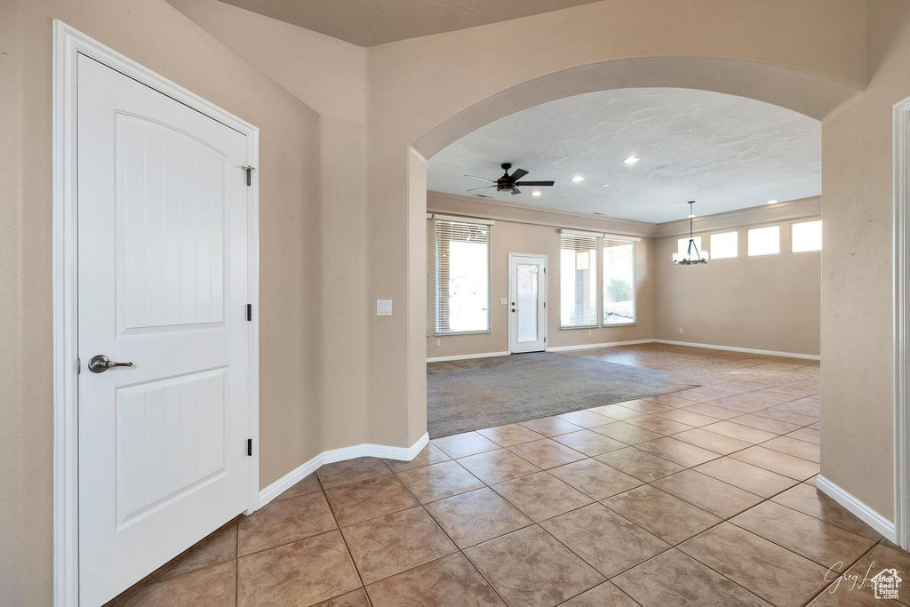 Tiled foyer entrance with ceiling fan with notable chandelier