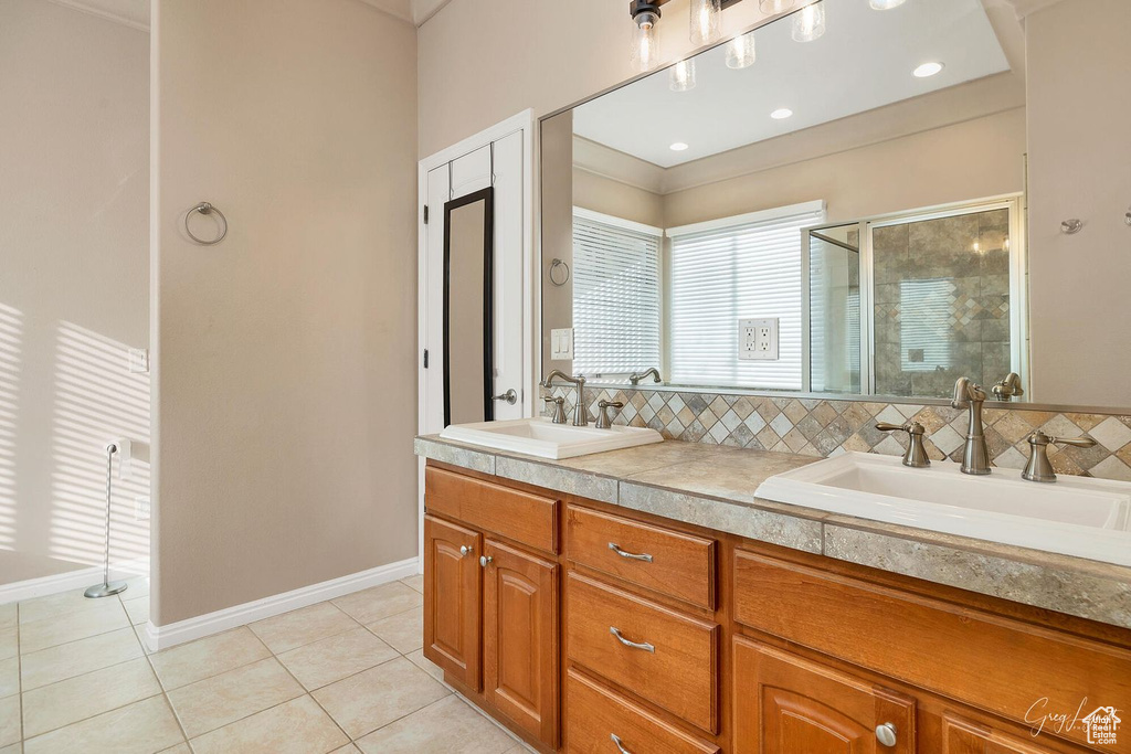 Bathroom featuring double vanity, tasteful backsplash, and tile flooring