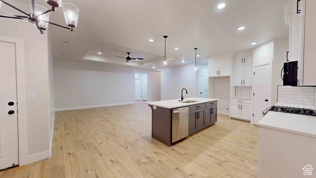 Kitchen with white cabinetry, sink, light hardwood / wood-style floors, an island with sink, and stainless steel dishwasher