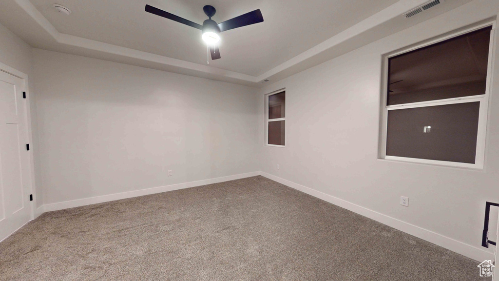 Carpeted empty room with a tray ceiling and ceiling fan