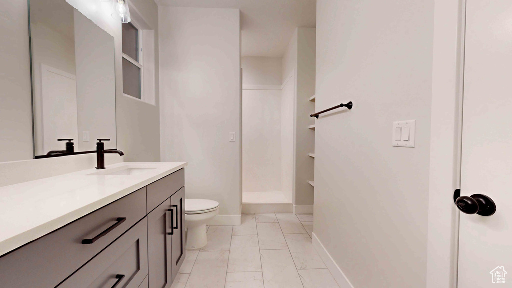 Bathroom with vanity with extensive cabinet space, tile floors, and toilet