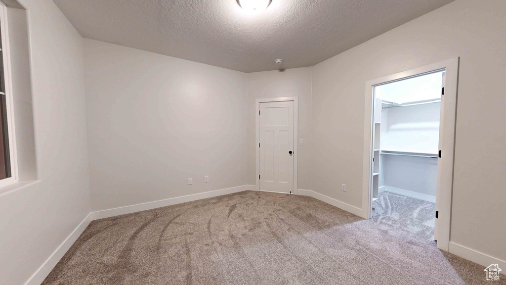 Empty room featuring light colored carpet and a textured ceiling