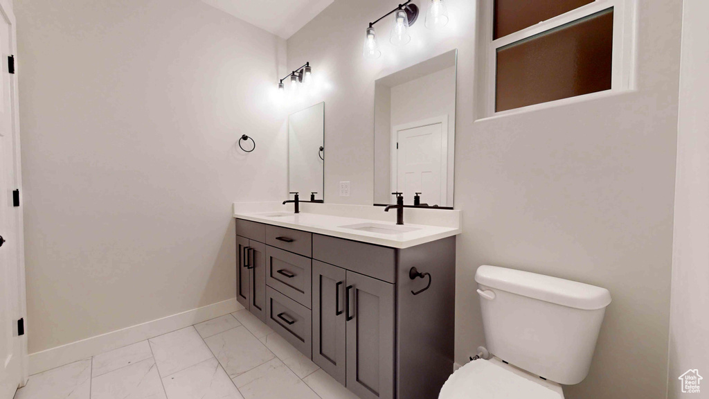 Bathroom featuring tile floors, double sink vanity, and toilet