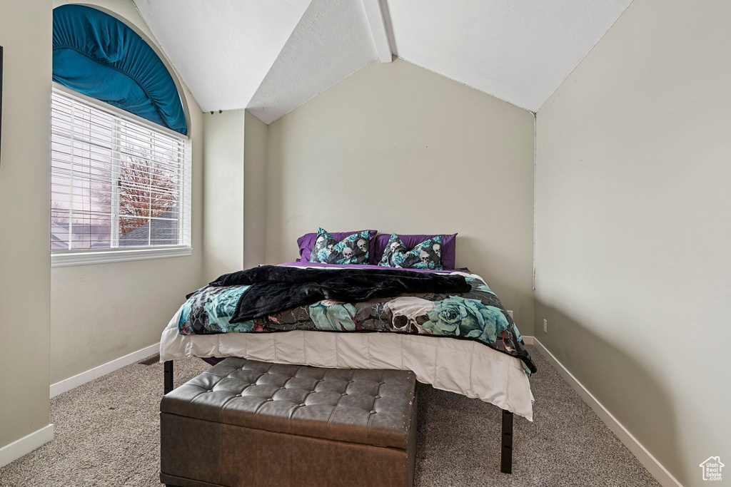Carpeted bedroom with lofted ceiling with beams