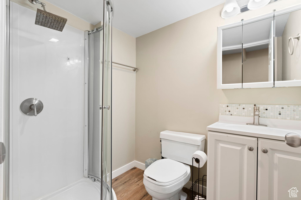 Bathroom featuring large vanity, toilet, an enclosed shower, and hardwood / wood-style flooring