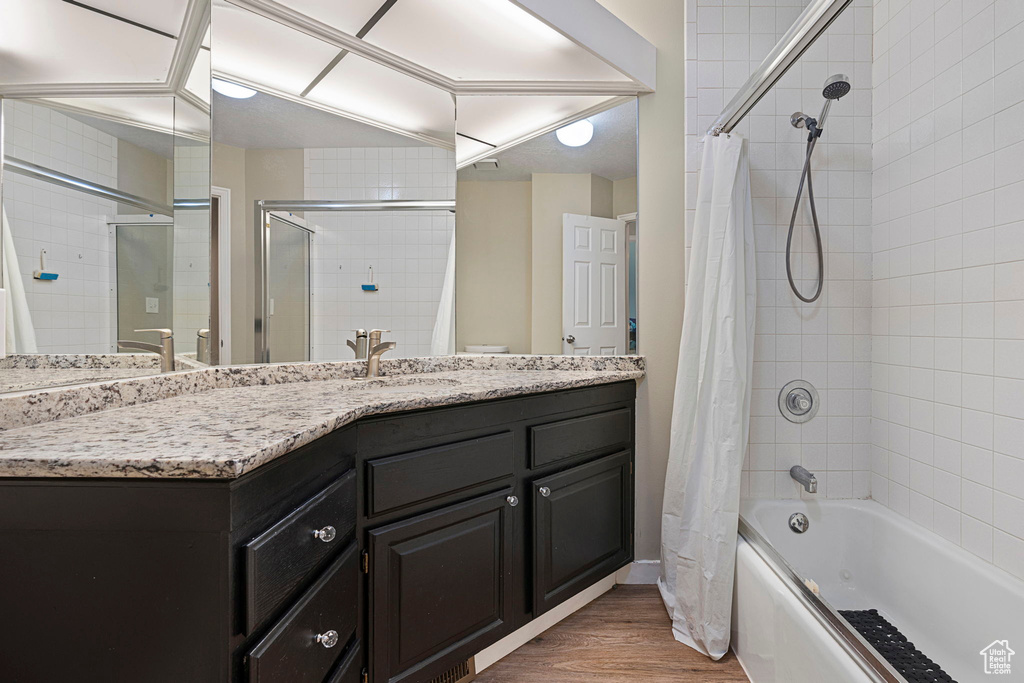 Bathroom with shower / bath combination with curtain, hardwood / wood-style floors, and vanity