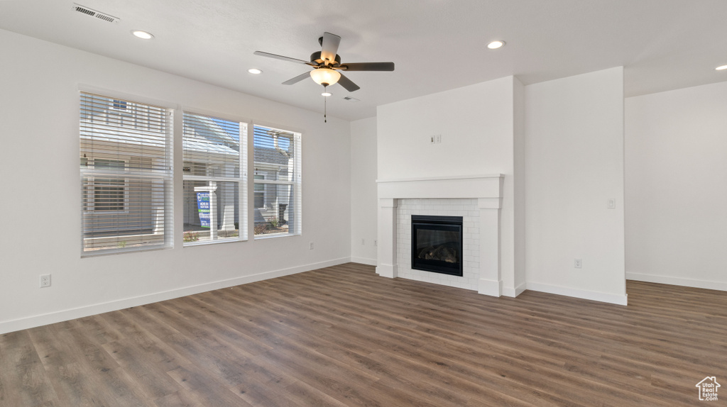 Unfurnished living room with dark wood-type flooring, a fireplace, and ceiling fan