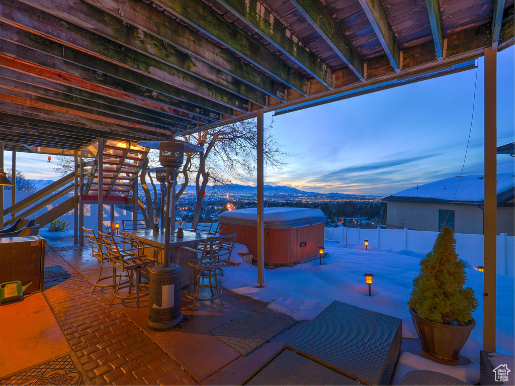 Patio terrace at dusk featuring a mountain view and a hot tub