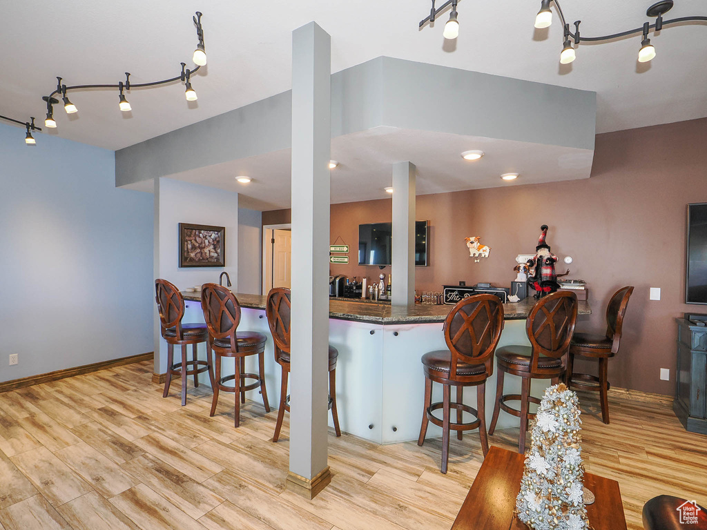 Kitchen featuring rail lighting, light hardwood / wood-style floors, and a kitchen bar