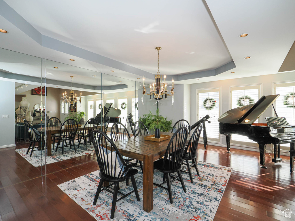 Dining room with an inviting chandelier, dark hardwood / wood-style flooring, a healthy amount of sunlight, and a tray ceiling