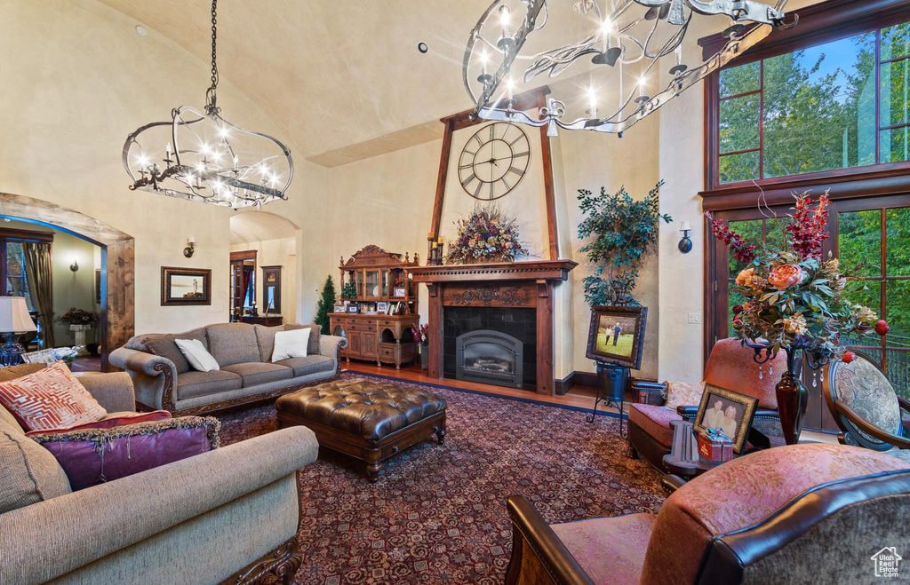 Living room featuring a tiled fireplace, an inviting chandelier, a wealth of natural light, and high vaulted ceiling