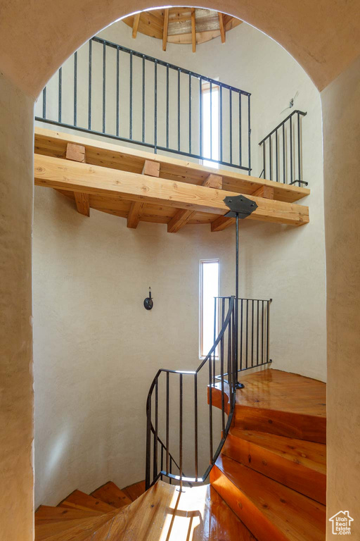 Stairway with beamed ceiling and a high ceiling