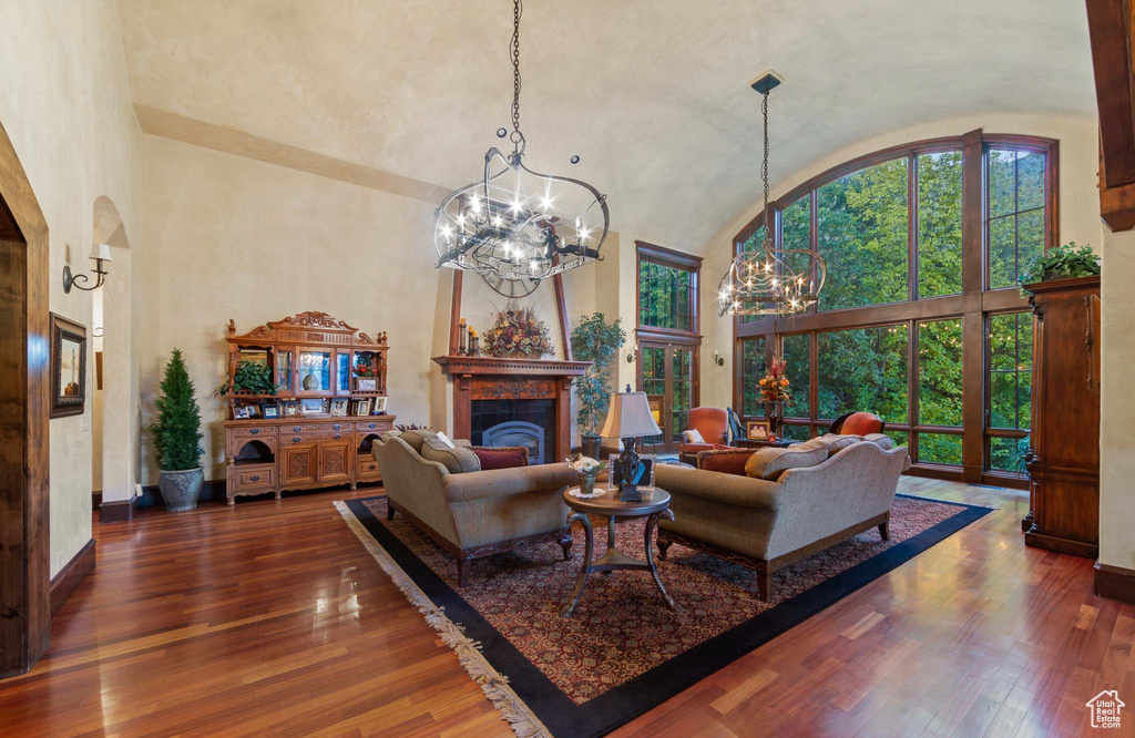 Living room featuring dark hardwood / wood-style flooring, an inviting chandelier, and high vaulted ceiling