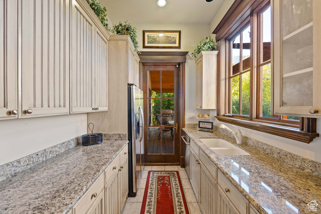 Kitchen featuring sink, light tile flooring, light stone counters, and a healthy amount of sunlight