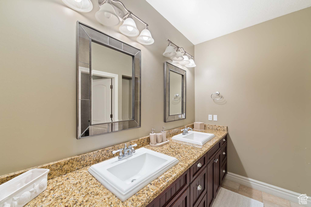 Bathroom with dual sinks, tile floors, and large vanity