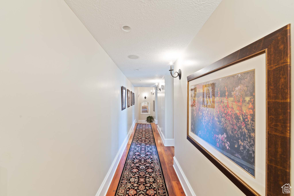 Corridor with dark hardwood / wood-style floors and a textured ceiling