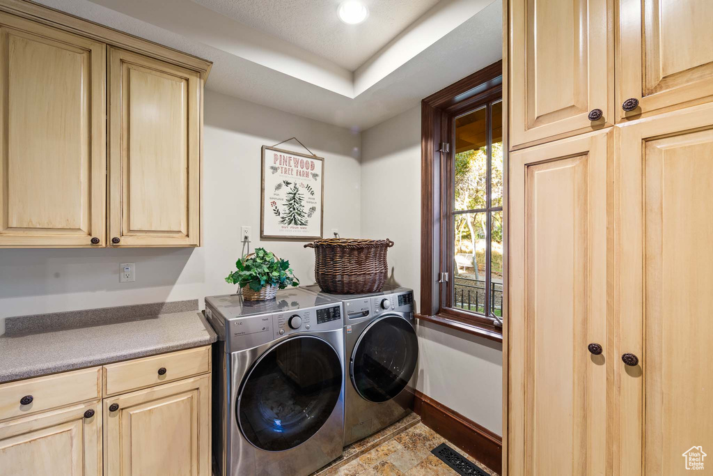 Laundry area with tile flooring, washer and clothes dryer, and cabinets